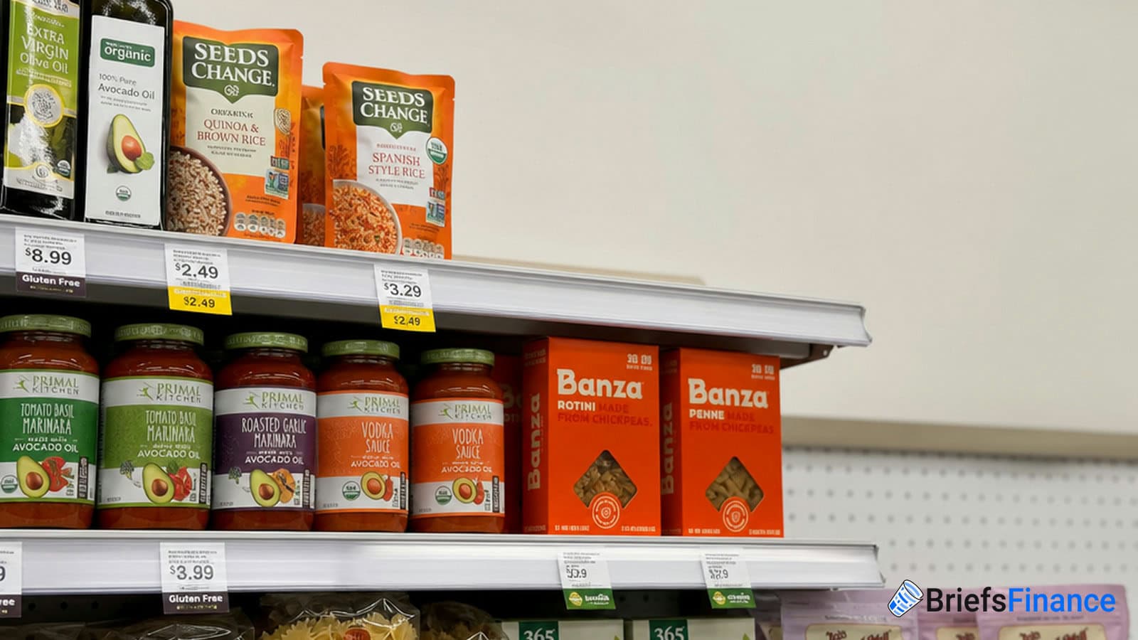Grocery store shelf displaying Seeds of Change rice packs, Primal Kitchen pasta sauces, and Banza chickpea pasta boxes. Price tags are visible below each item.
